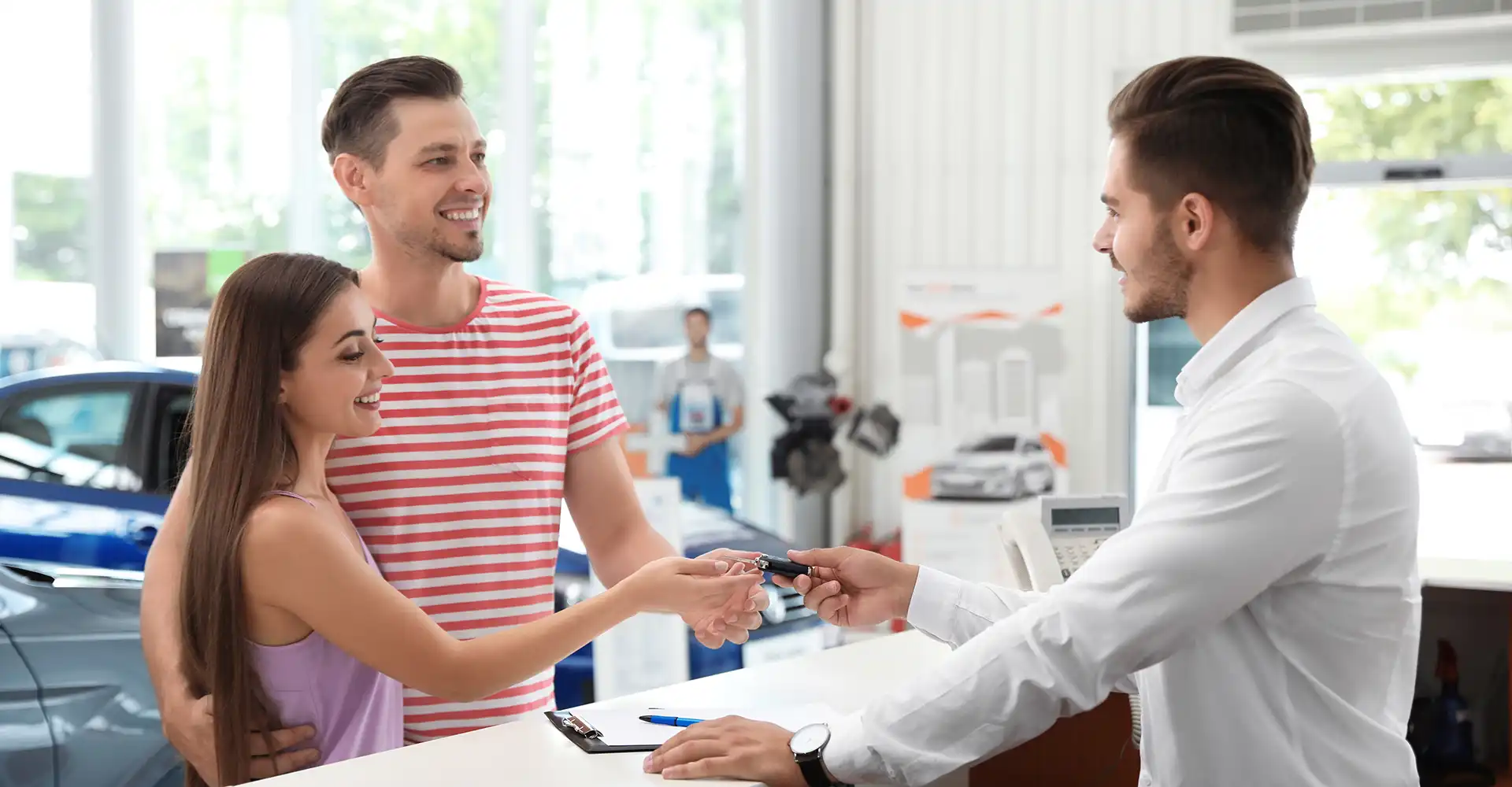 Happy dealership customers receiving keys from a service advisor