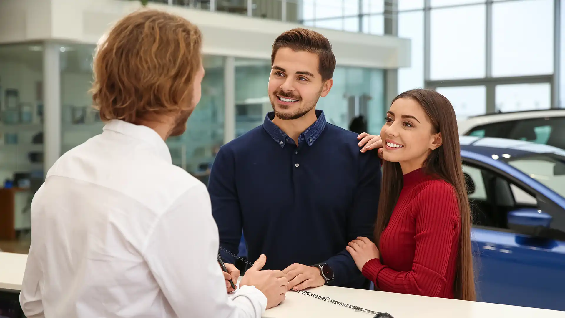 Happy couple speaking with a dealership service advisor at a service desk